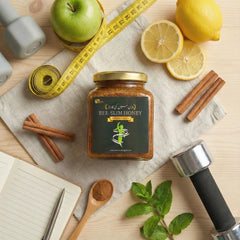 Jar of Bee Slim Honey surrounded by apples, lemons, cinnamon sticks, and a measuring tape on a wooden surface.