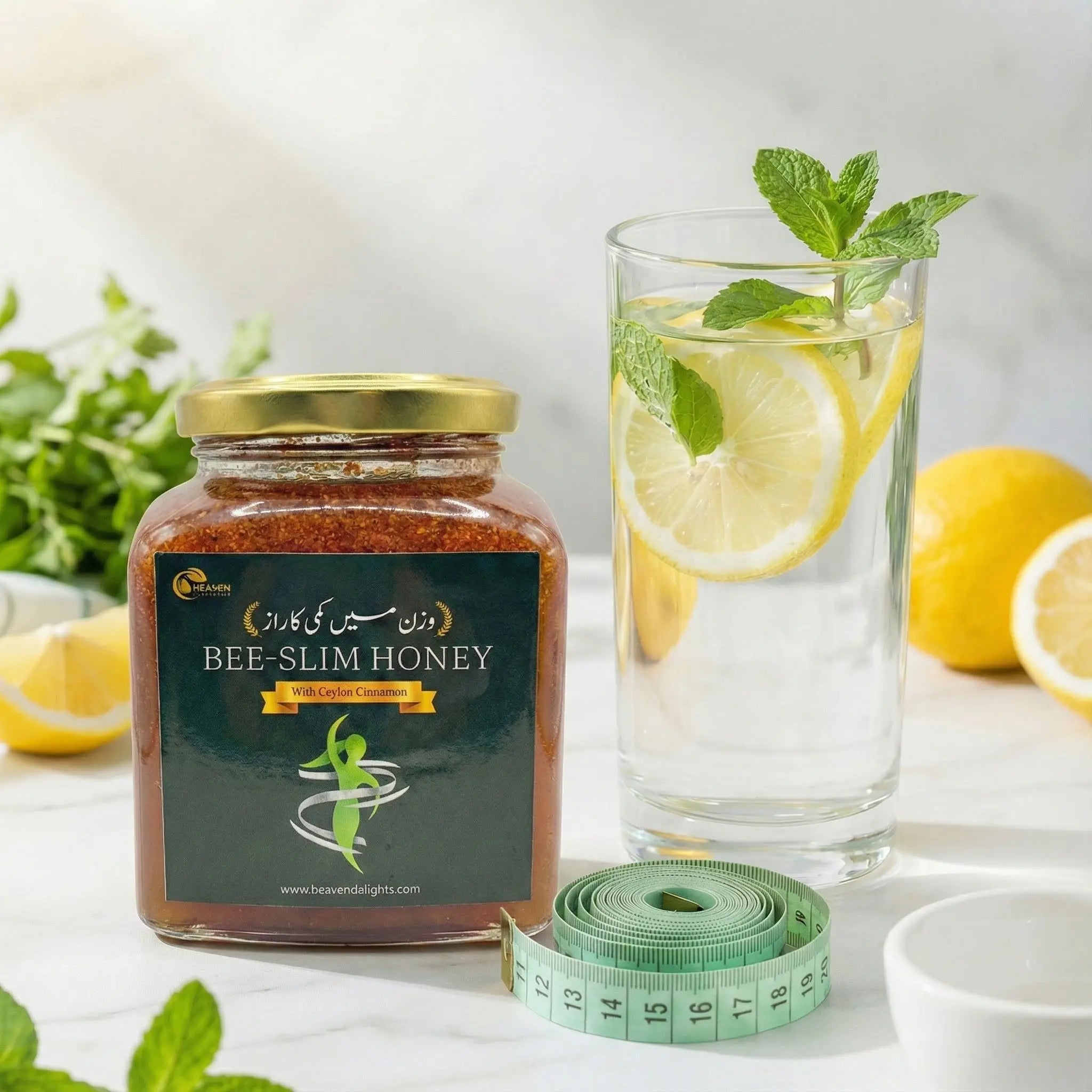Jar of Bee-Slim Honey with a glass of lemon water, lemons, and a measuring tape on a white surface.