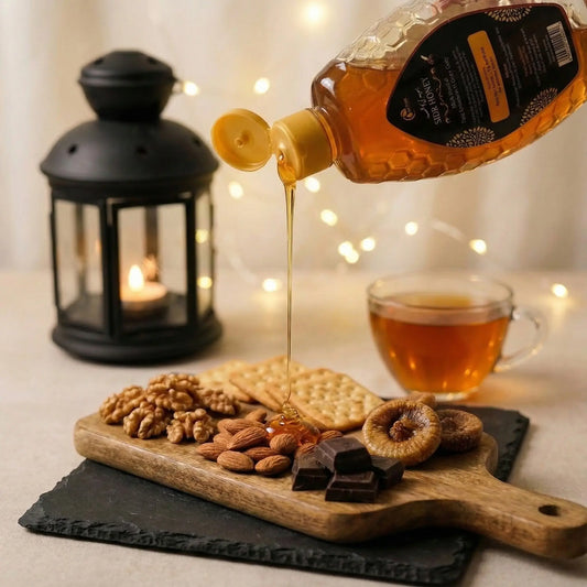 Honey being poured from a jar onto a wooden board with snacks and a lit candle in the background.