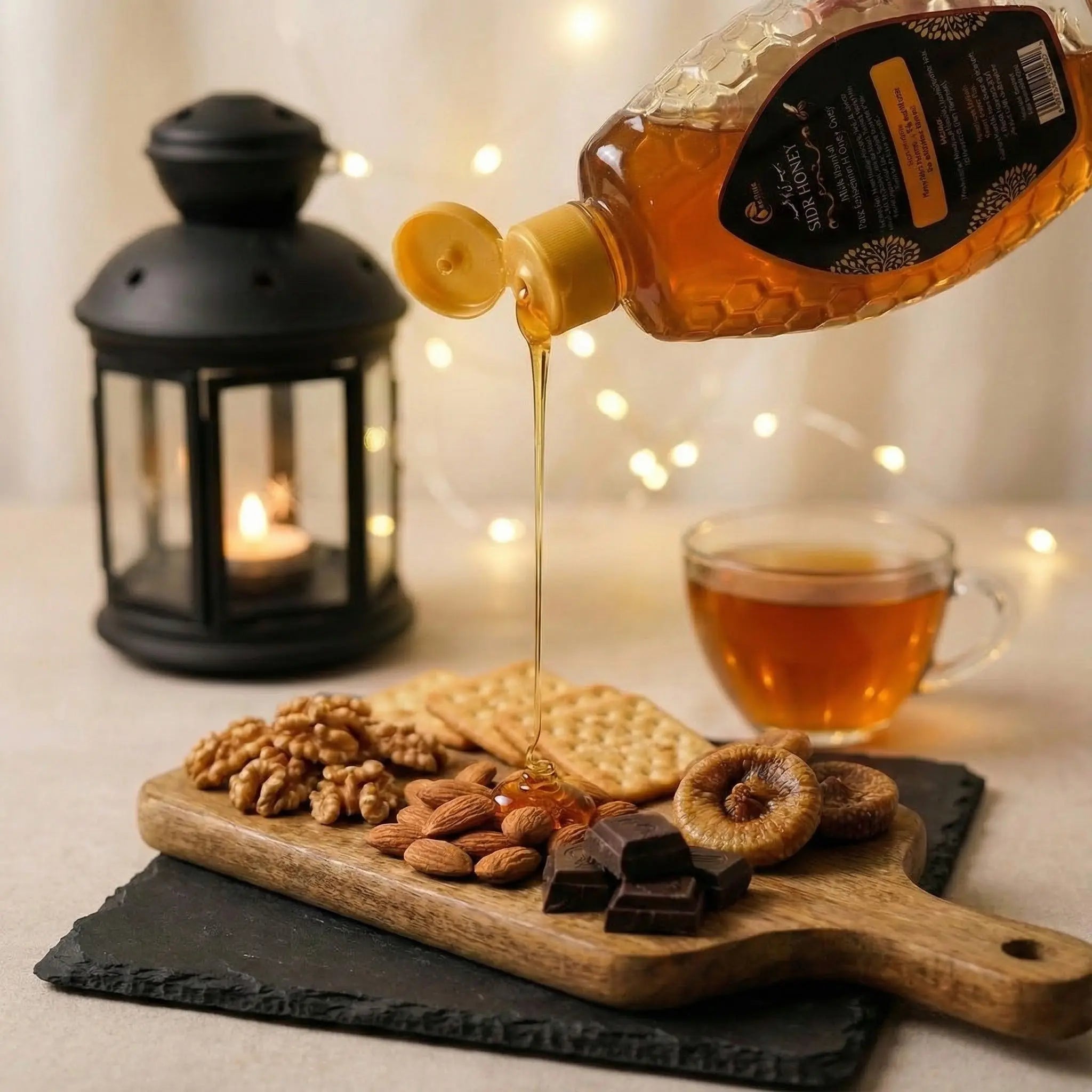 Honey being poured from a jar onto a wooden board with snacks and a lit candle in the background.